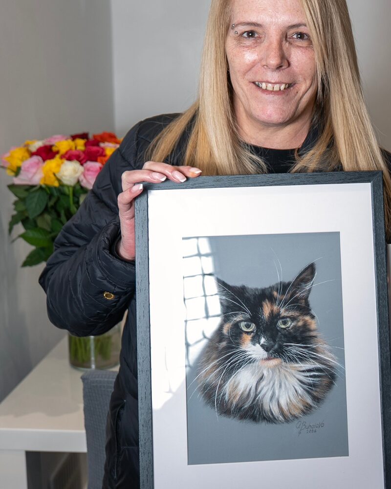 Belle's owner holding the framed coloured pencil portrait