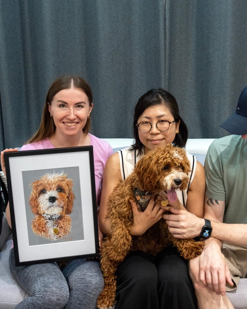 Oksana with the framed portrait of Haku, beside Haku and his owners