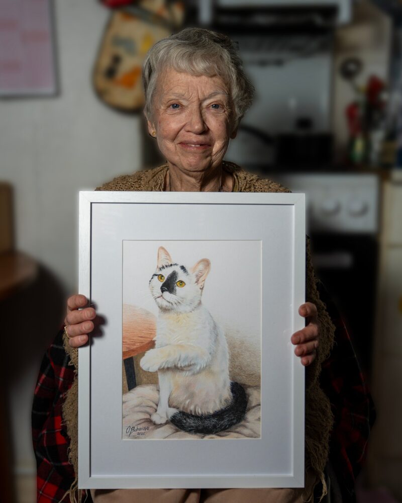 Margaret holding a framed coloured pencil portrait of her cat