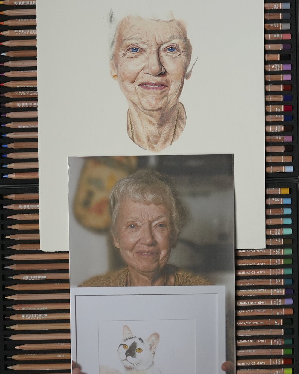 A coloured pencil portrait of Margaret halfway through, with the reference photograph laid beneath it