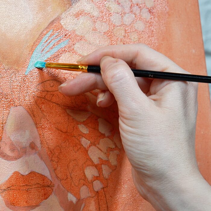Oksana's hand working with a fine brush